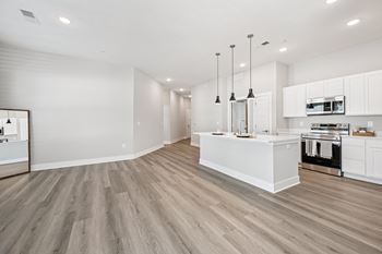 A modern kitchen with a white island and wooden floors.